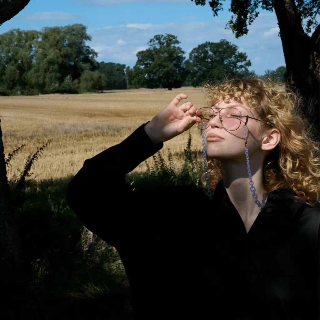Frau mit Coblens Brille im Sonnenlicht auf Feld.