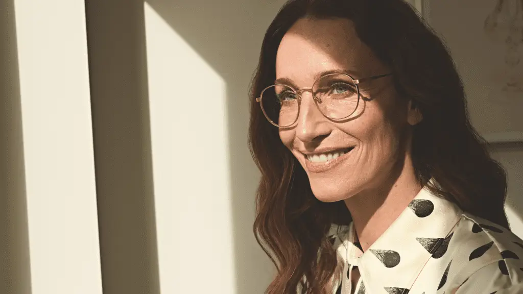 Frau mit feiner Götti Brille lächelt gegen Licht.