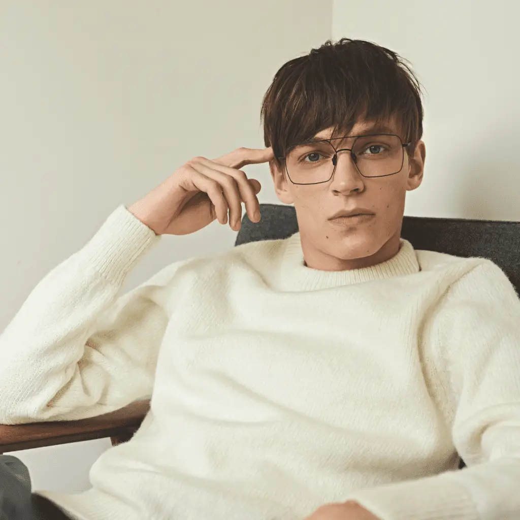 Junger Mann mit Götti-Brille und weißem Pullover.