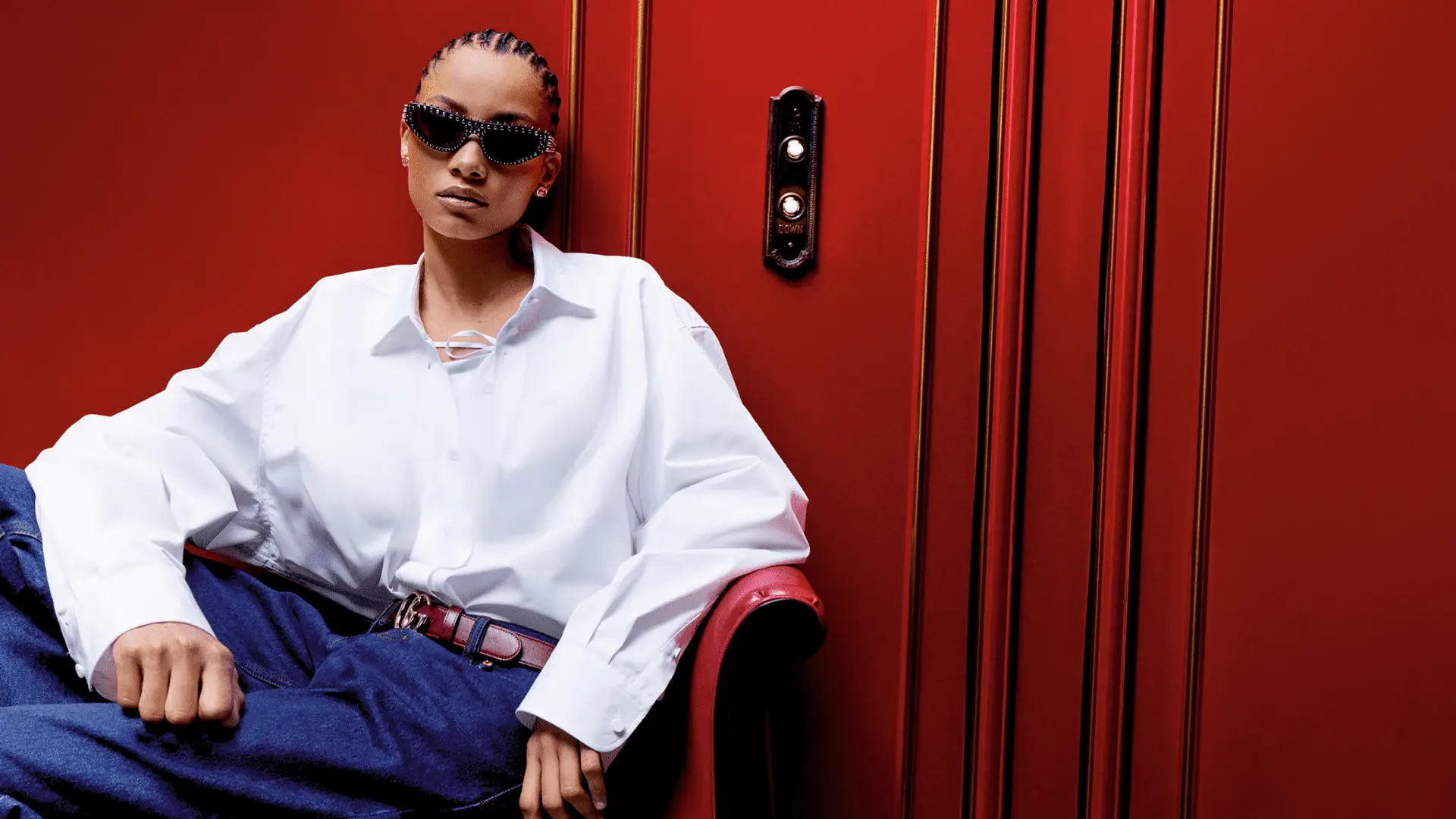 Frau mit Gucci Brille in stilvoller Kleidung vor rotem Hintergrund