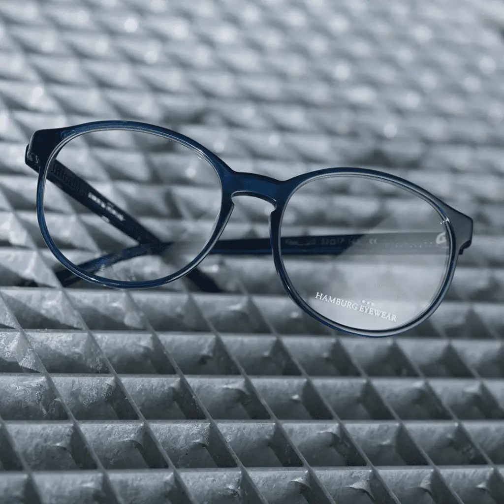 Blaue Brille von Hamburg Eyewear auf metallischer Oberfläche.